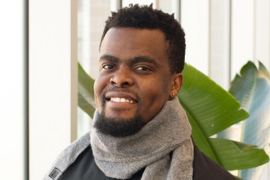 Young man with a scarf around his neck smiling.